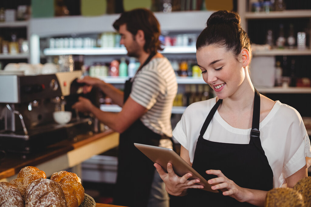 Vrouwelijke serveerster in een café houdt een tablet in haar hand