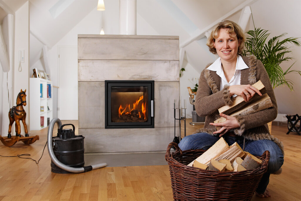 Vrouw met hout op arm voor open haard en aszuiger