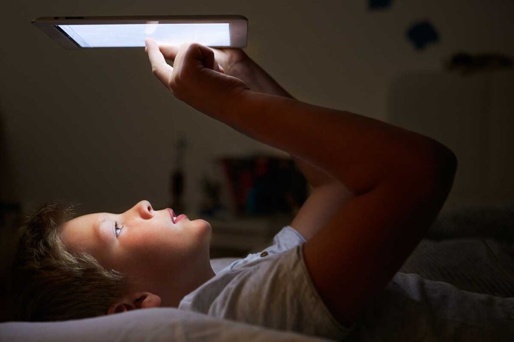 jongen ligt in bed en leest in zijn boek