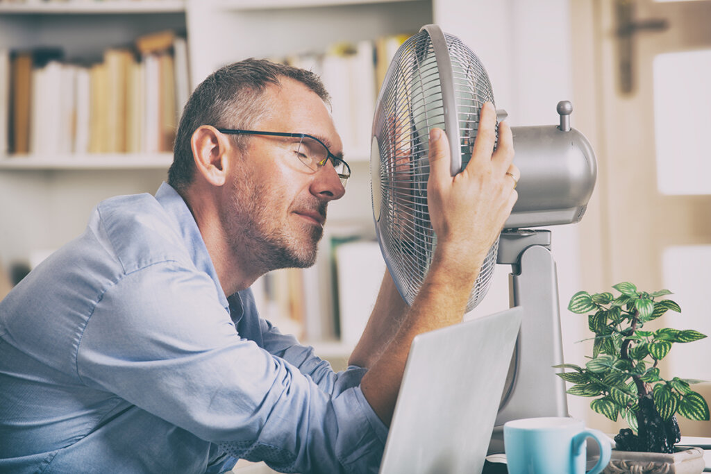 man voor ventilator in kantoor