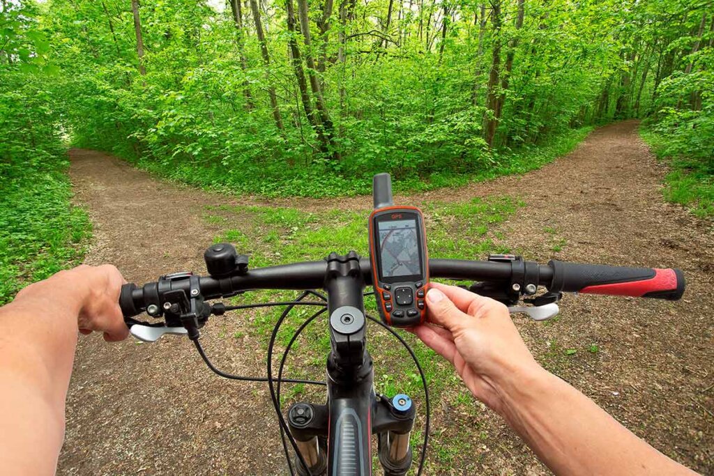 fietser kijkt op zijn navi voordat hij een pad in het bos oversteekt