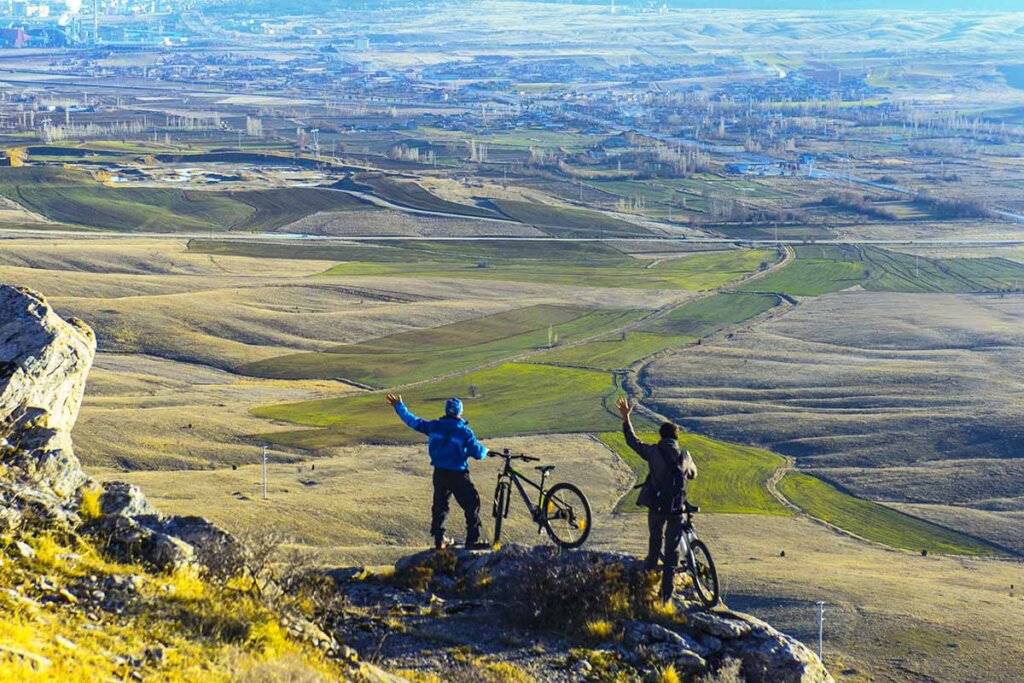 fietser staat op een berg en kijkt neer op het landschap