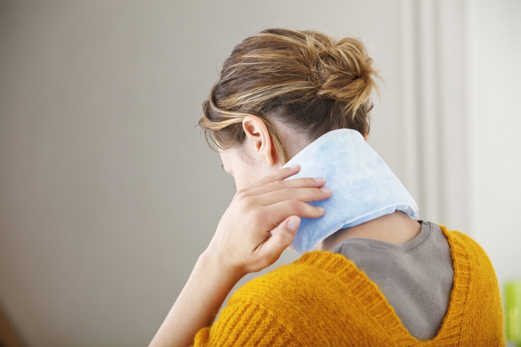 vrouw heeft verwarmingskussen in nek