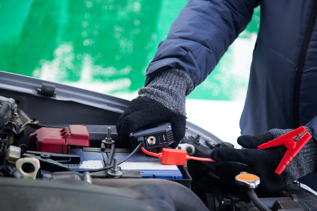 Man sluit jump starter aan op autoaccu