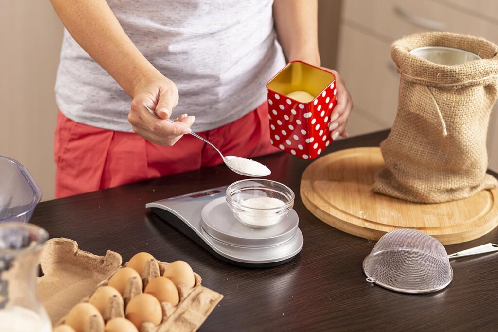 Vrouw die suiker meet in keuken