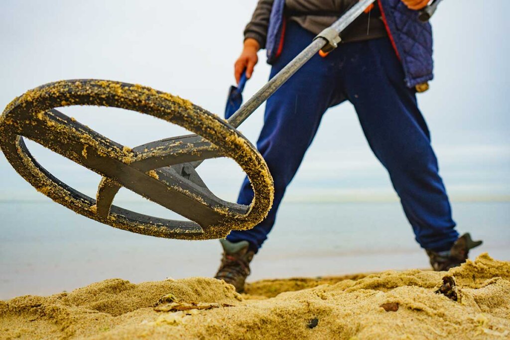 Man met metaaldetector in het zand