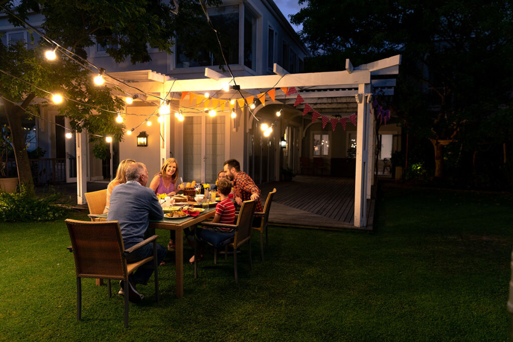 familie eet samen in de tuin met lichtketting