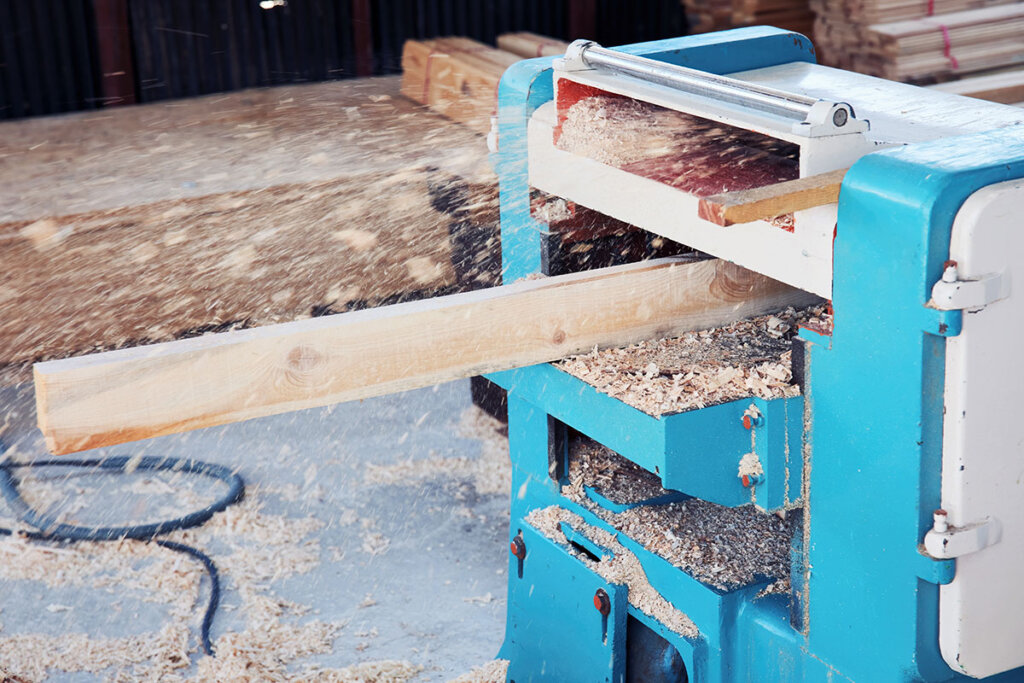 Hout wordt geschaafd met een grote stationaire schaafmachine