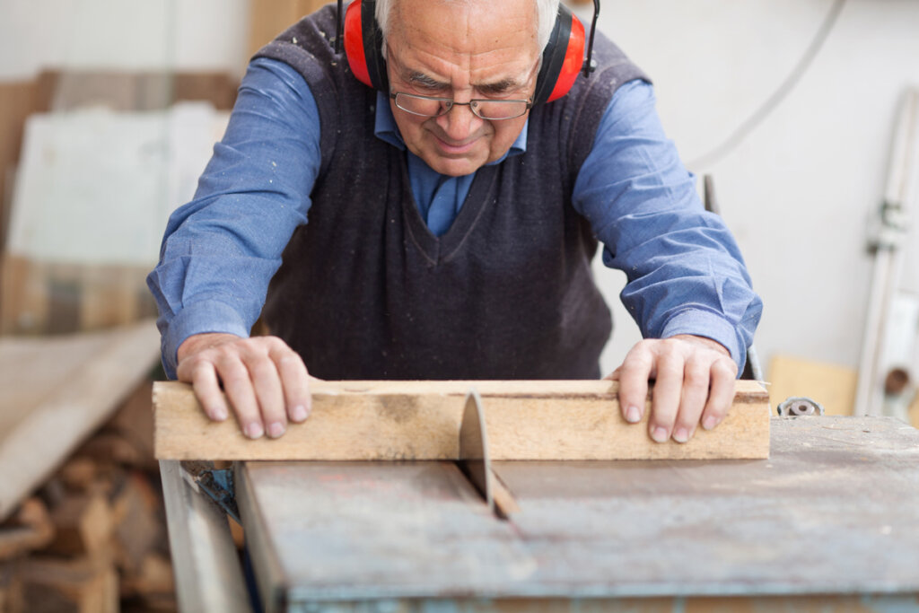 Man die hout met tafelzaag zaagt