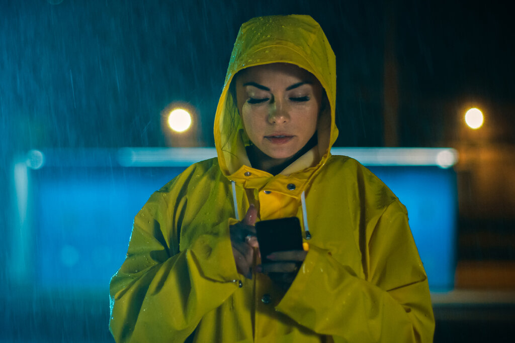 Vrouw in de regen gebruikt smartphone