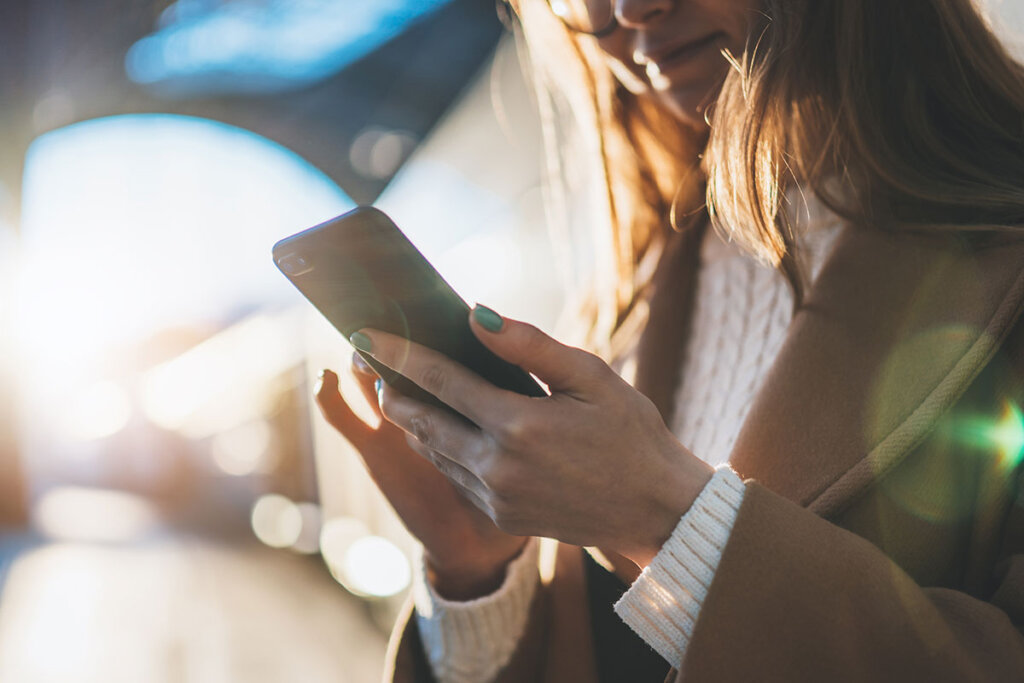 Vrouw houdt smartphone vast op treinstation