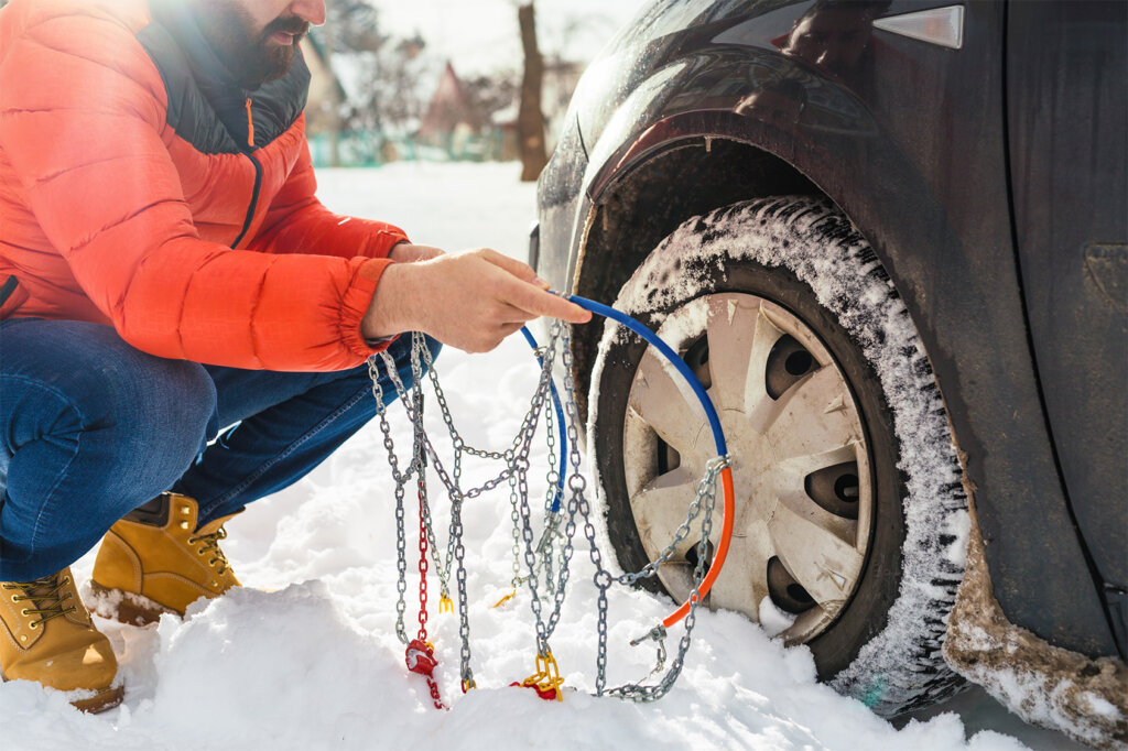 man_puts_on_snow_chains