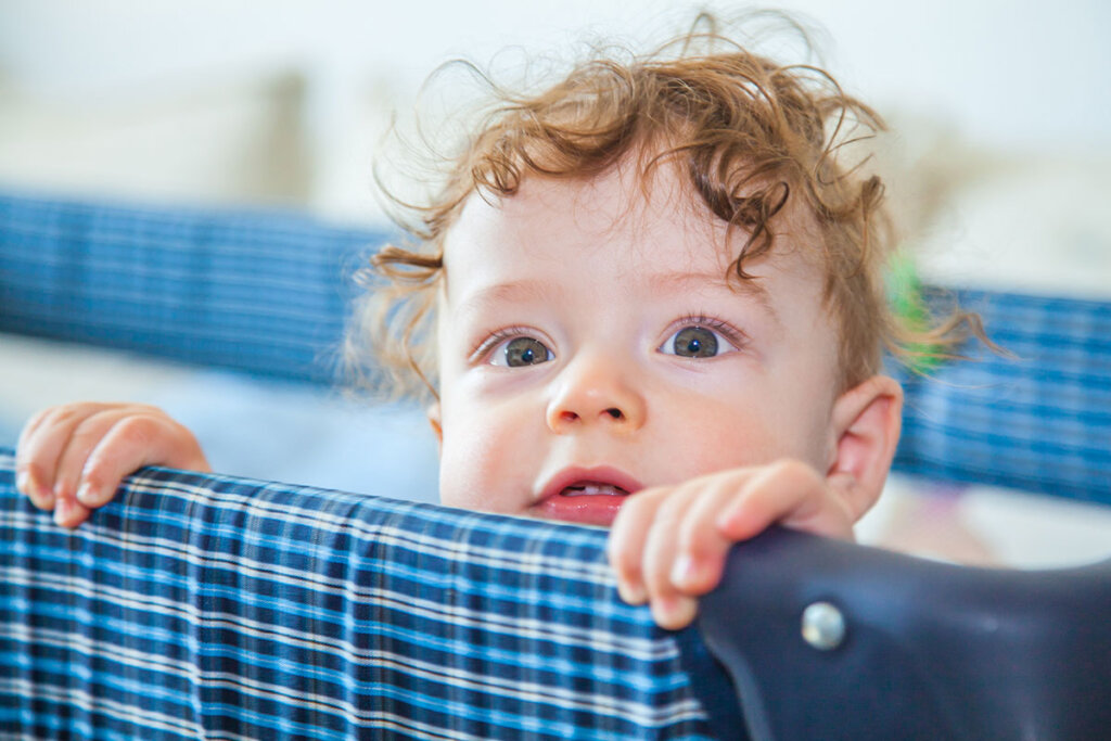 Baby in reiswieg kijkt over de rand