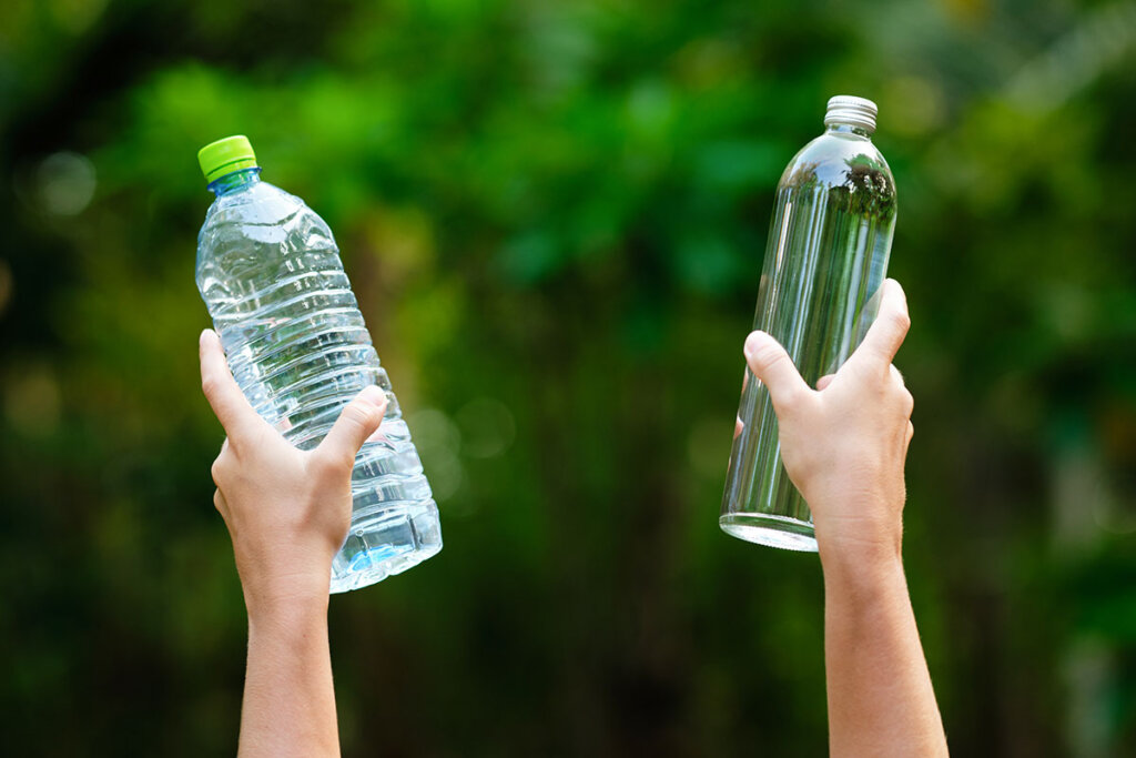 handen houden plastic en glazen fles omho