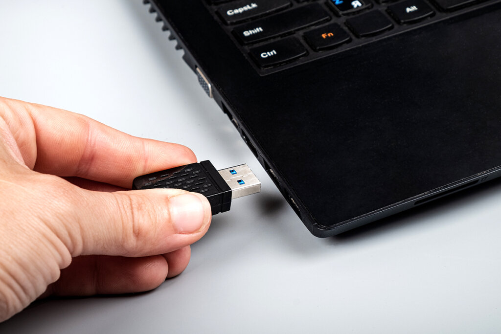 Persoon steekt WLAN-stick in USB-sleuf op laptop